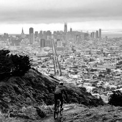 Man riding motorcycle on cityscape against sky