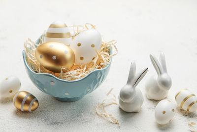 Decorative rabbits and a bowl with easter eggs on the table. the concept of easter holidays.