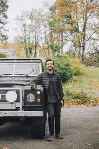 Mid adult man standing by sports utility vehicle on driveway