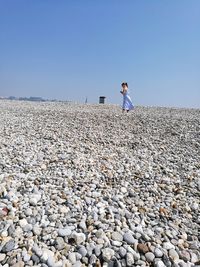 Full length of girl standing on rocks against clear sky