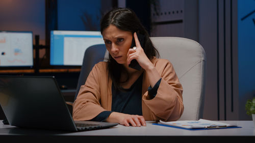 Woman talking on phone while sitting in office