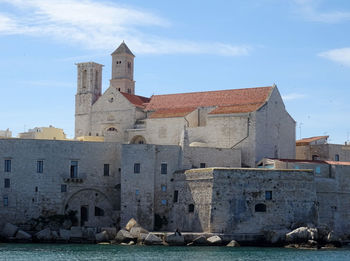 Old building by sea against sky