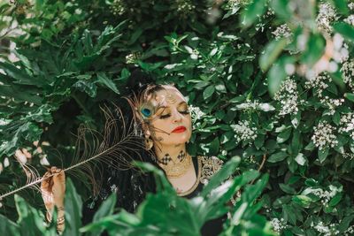 Close-up of woman with make-up amidst plants