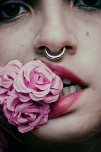 Close-up portrait of woman biting artificial rose