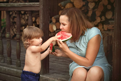 Cute son feeding watermelon to mother outdoors