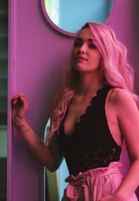Young woman standing on pink indoors