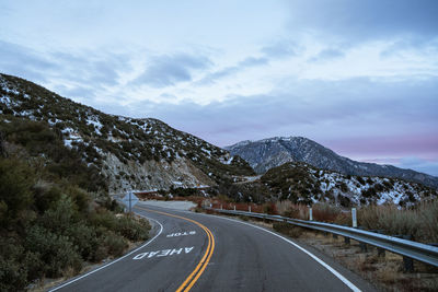 Empty road along mountain range against sky