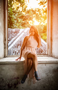 Young woman sitting against window