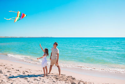 Full length of friends on beach against sky