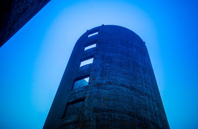 Low angle view of old tower against clear blue sky