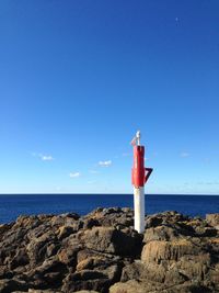 Lighthouse by sea against blue sky