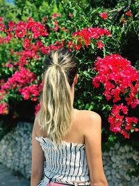 Rear view of woman standing against flowering plants