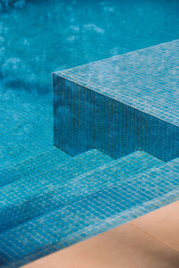From above of tiled bottom and steps in swimming pool with clean blue water