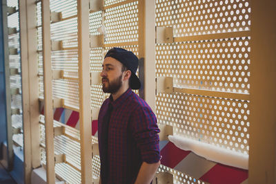 Young man standing by metal wall