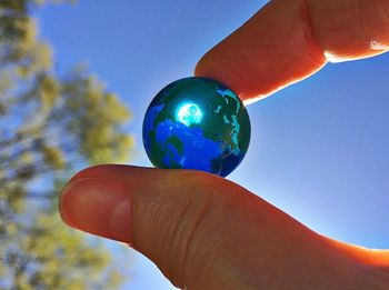 Low angle view of cropped hand against blue sky