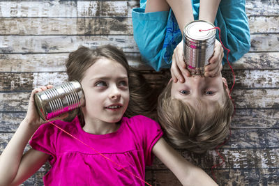 Portrait of brother and little sister playing with tin can phone