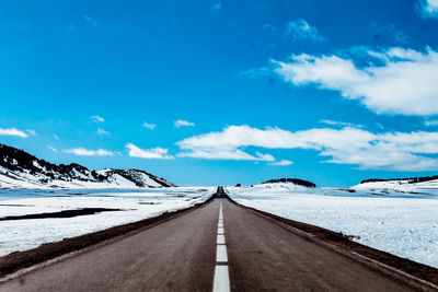 Road leading towards snowcapped mountains against sky