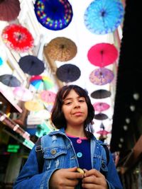 Portrait of girl standing against multi colored umbrellas