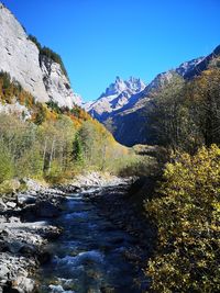 Scenic view of stream by mountains against clear sky