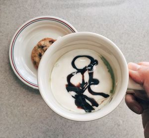 Directly above shot of hand holding coffee cup on table