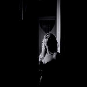 Mid adult woman looking up while standing at doorway in darkroom