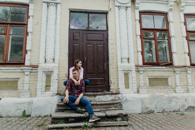 Full length of woman sitting outside house