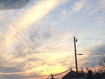 Low angle view of power lines against cloudy sky