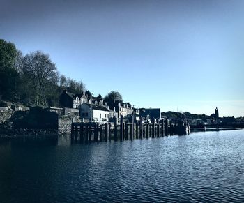 Scenic view of river by building against clear blue sky