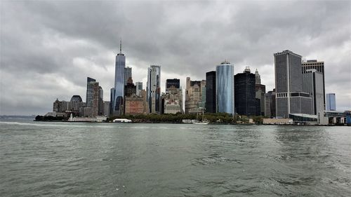 Sea by modern buildings against sky in city