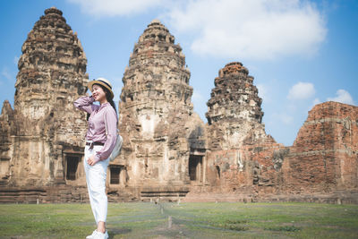 Smiling woman standing on land against old temples