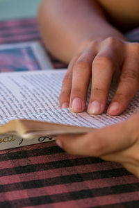 Cropped hands of person reading book on table