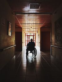 Rear view of man sitting in corridor of building