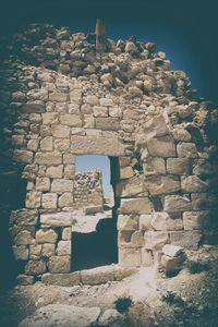 Stone wall in front of built structure against the sky