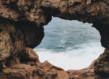 Scenic view of sea seen through hole in rock formation