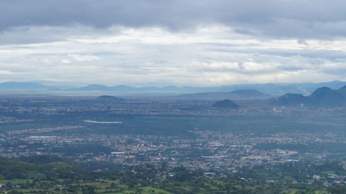 Aerial view of cityscape against cloudy sky