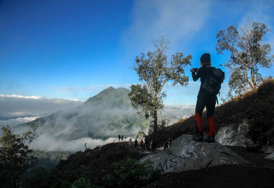 Woman standing on mountain against sky