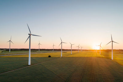 Wind turbines on grassy field against clear sky