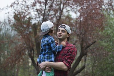 Portrait of father carrying son against trees