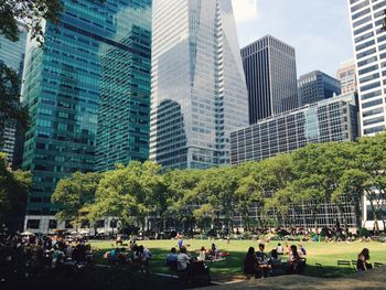 People relaxing at bryant park against buildings in city