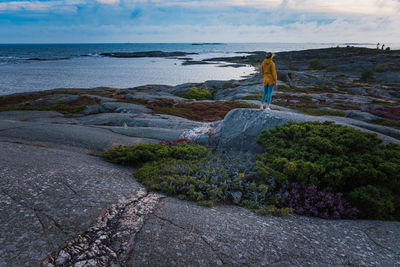 Woman standing on rock at beach against sky