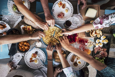 Cropped hands of friends having food at table