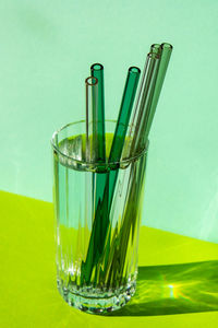 Reusable glass straws in glass with water on green background eco-friendly drinking straw set with