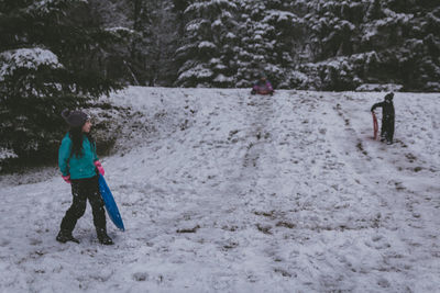 Full length of girls standing on bobsled in snow