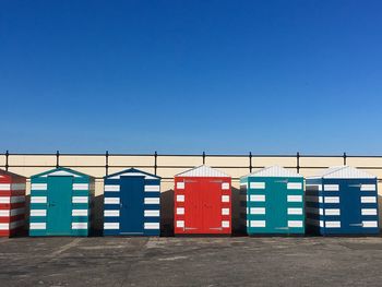 Colourful huts on beach against clear blue sky 