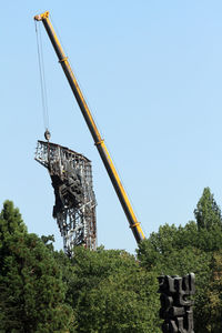 Low angle view of crane at construction site against clear sky