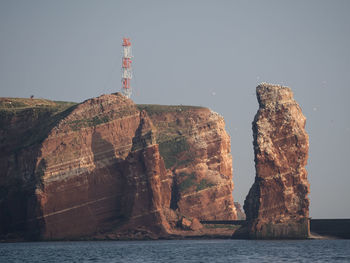 Rock formations in sea against clear sky