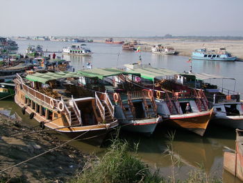 Boats moored at harbor against sky