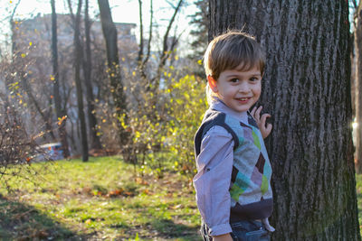 A little child stands near a tree in an autumn park