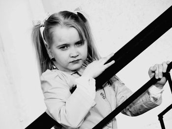 Portrait of girl leaning on railing against wall