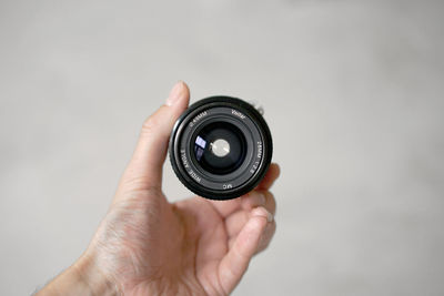 Close-up of hand holding camera against white background